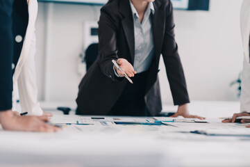 Businesswoman passing a pen to her colleague during a meeting over documents with graphs and financial data