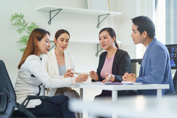 Asian businesspeople collaborating in a bright office, sharing ideas and strategies while working together on a project for success