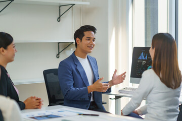 Asian businessman leading a meeting explaining strategy to colleagues in the office using a computer, teamwork and business concept