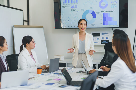 Businesswoman presenting company performance data to colleagues during a meeting in a modern office