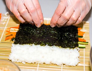 Gloved hands carefully roll sushi on a bamboo mat
