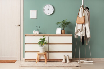 Interior of hallway with wall clock, commode and clothes rack
