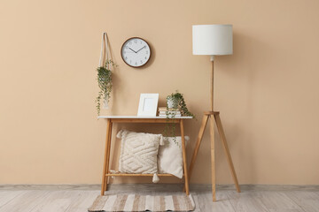 Interior of room with table, lamp and clock on beige wall