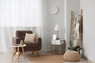Interior of living room with wall clock, armchair and tables