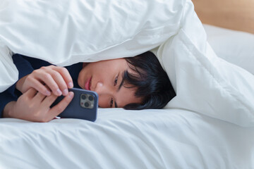 ベッドでスマホを使う男性
