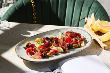 Meat antipasti with olives in bright natural lighting, overhead restaurant-style composition