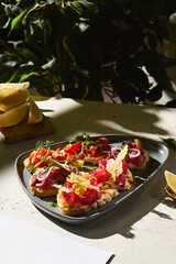 Assorted bruschetta on triangular plate in bright sunlight, overhead composition