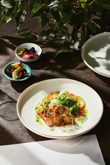 Baked potato wedges rustic bright overhead on ceramic plate with colorful vegetables and moody table setting
