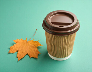 Takeaway coffee cup with autumn leaves and a straw on a textured background
