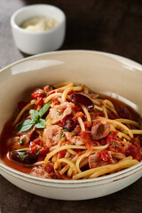 Spaghetti with tomatoes and kalamata olives, bright rustic lighting, closeup composition