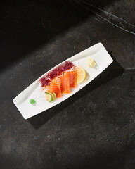 Salmon sashimi with lemon and garnish, bright lighting, overhead composition