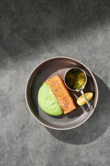 Grilled salmon steak with wasabi puree, bright top-down overhead composition on ceramic plate