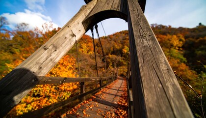 Low-angle view of a rustic wooden suspension bridge amidst vibrant autumn foliage