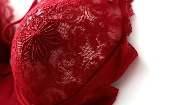 Closeup of a red lace bra against a white background showcasing intricate floral details