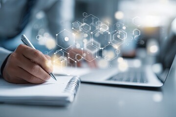 Close-up of person writing notes with a pen, laptop in background, abstract hexagonal shapes