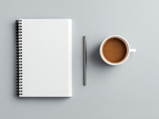 White spiral notebook, silver pen, and cup of coffee are neatly arranged on gray background, evoking simplicity and focus