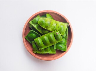 Raw Petai (Parkia Speciosa) or Bitter Bean in a wooden plate on a white background.