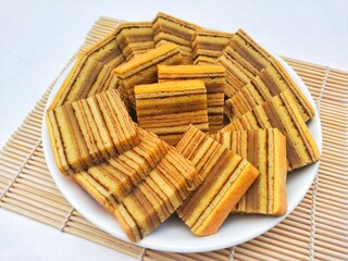 Layered cake (Kue Lapis Legit) in a white plate on a white background. 