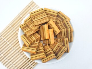 Layered cake (Kue Lapis Legit) in a white plate on a white background. 