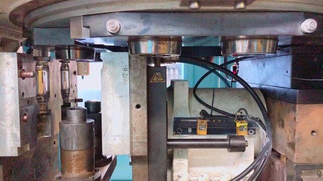 Blow molding machine producing clear plastic bottles on factory production line.