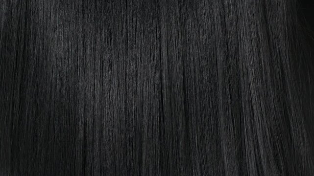 Closeup human long hair texture in slow motion, black straight hair background