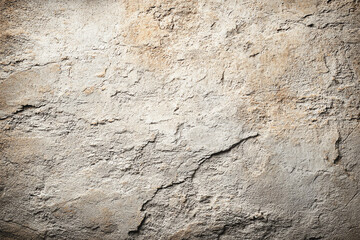 Rough textured beige and light brown concrete wall with cracks and weathered surface.