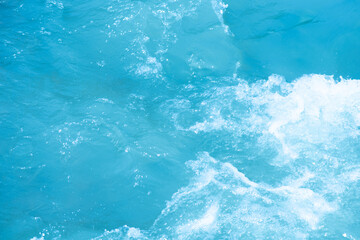 Blue water with ripples on the surface. Defocus blurred transparent blue colored clear calm water surface texture with splashes and bubbles. Water waves with shining pattern texture background.