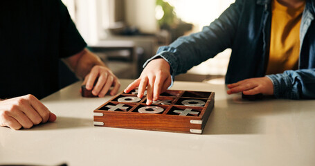 Board game, development and hands of child with parent in home together, playing tic tac toe. Fun, strategy or thinking with father and son in apartment for noughts and crosses competition or contest