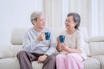 Obraz premium Happy Senior Couple Drinking Coffee and Talking on the Couch