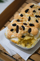 Manado's signature klapertart topped with almonds and raisins, served in individual containers. A rich and delicious creamy coconut dessert