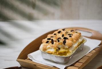 Manado's signature klapertart topped with almonds and raisins, served in individual containers. A rich and delicious creamy coconut dessert