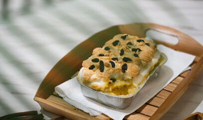 Manado's signature klapertart topped with almonds and raisins, served in individual containers. A rich and delicious creamy coconut dessert