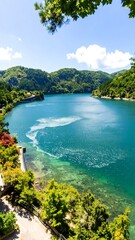 Tranquil lake scene showcasing lush greenery, crystal-clear water, and a picturesque shoreline.  A stunning vista of a calm lake surrounded by vibrant green hills under a bright sunny sky.