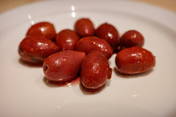 Close-up of red olives on a white plate, Mediterranean appetizer