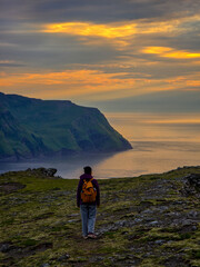 Fototapeta premium Stunning sunset view over the cliffs of Faroe Islands with a lone hiker enjoying natures beauty
