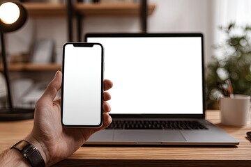 Hand holding a phone next to a laptop