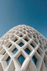 Modern, light-beige building facade, patterned with diamond-shaped holes, against a clear blue sky