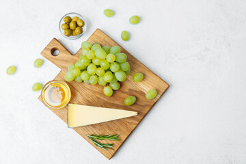 Delicious cheese platter with fresh grapes, olives, and honey on serving board
