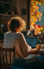 Obraz premium Woman working from home on laptop in cozy autumn setting
