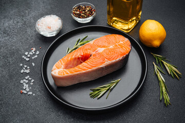 Salmon fillet preparation with spices and lemon on dark background