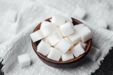 Sugar cubes stacked in a rustic bowl on a textured cloth setting