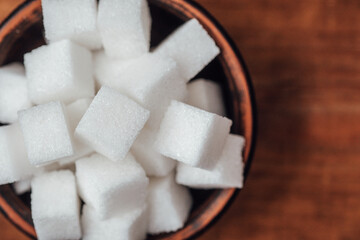 Cubes of sugar arranged in a bowl on a wooden surface