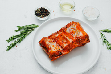 Marinated pork ribs on white plate with rosemary and spices
