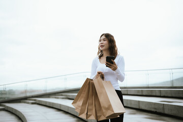 A cheerful young woman enjoys shopping in a luxury retail store, holding stylish bags with joy, glamour, and happiness in city life.