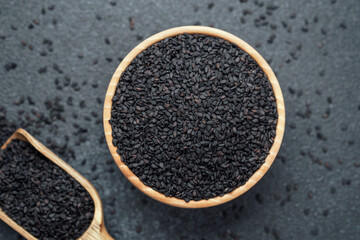 Black sesame seeds in bowl and scoop on dark background