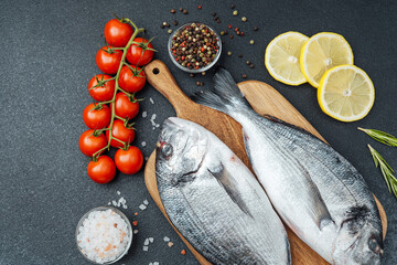 Raw dorado fish tomatoes lemon and spices on cutting board
