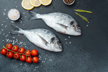 Top view of raw dorado fish with lemon pepper and rosemary on black background