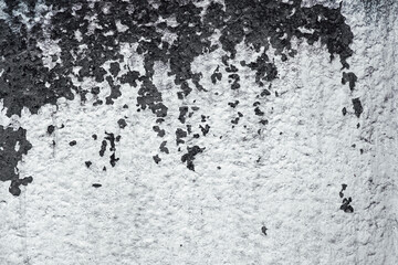 Textured surface with peeling dark paint on a rough white wall, abstract background