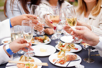 Sitting at the festive table, women clink glasses of champagne and make a toast.