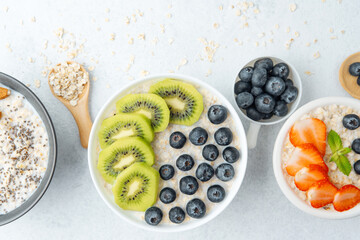 Flat lay of oatmeal bowls with fruits and oats on white background